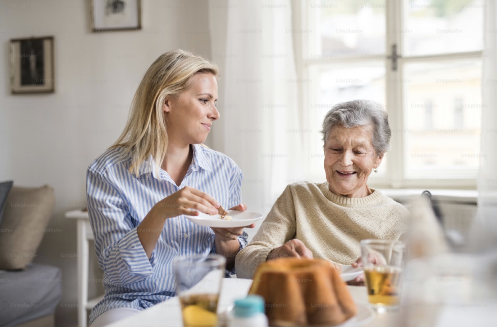 A care worker shares a meal at home with an older woman — personalised support, in everyday moments.